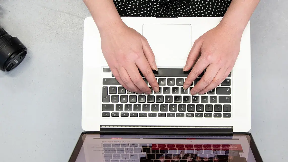 Studentin Crossmedia-Redaktion/Public Relations tippt auf Laptop zu sehen von oben.