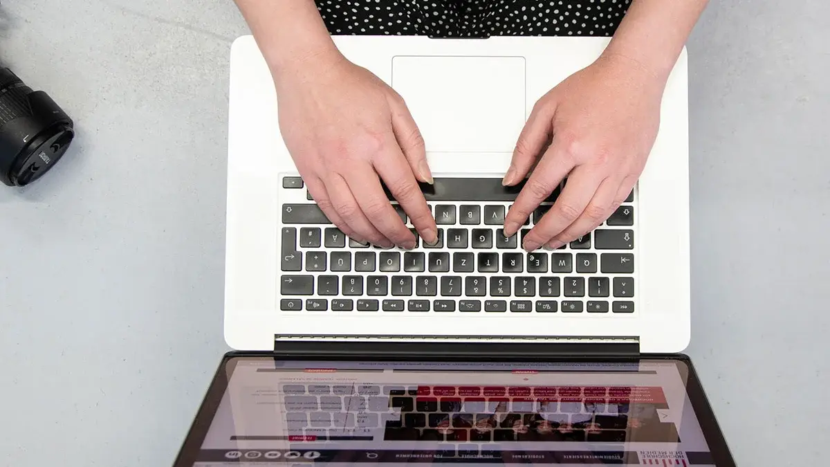 Studentin Crossmedia-Redaktion/Public Relations tippt auf Laptop zu sehen von oben.