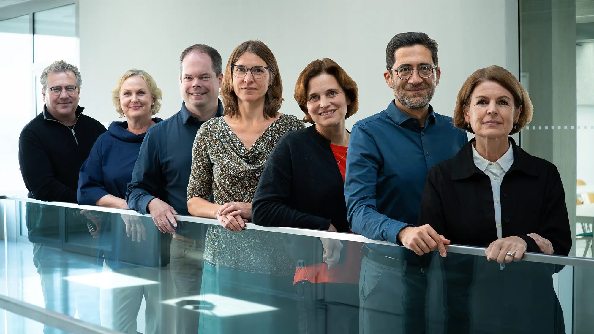 Teamfoto der Professorinnen des Studiengangs Crossmedia-Redaktion/Public Relations. Von hinten nach vorne: Prof. Dr. Klaus Kamps, Prof. Dr. Katrin Hassenstein, Prof. Dr. Alexander Mäder, Prof. Dr. Judith Pies, Prof. Dr. Katarina Bader, Prof. Dr. Swaran Sandhu, Prof. Christine Ritz.